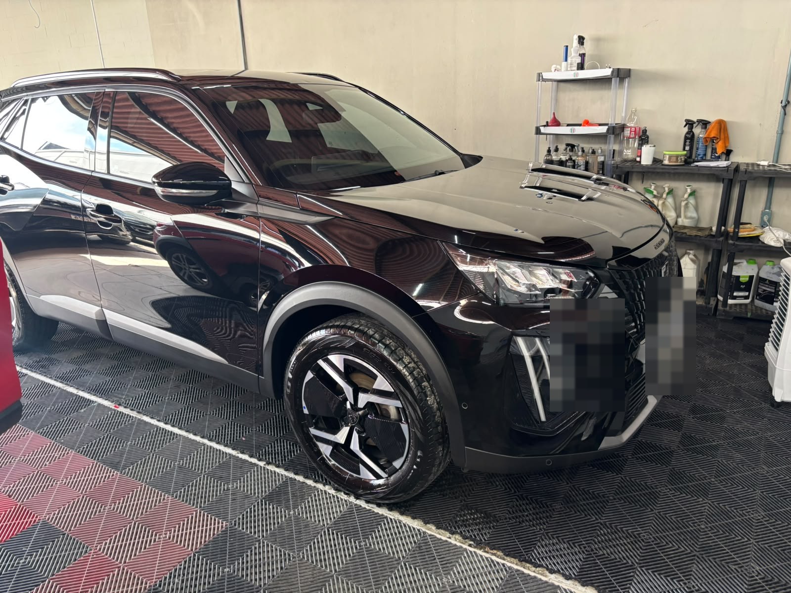SUV escura com acabamento brilhante no box de detalhamento